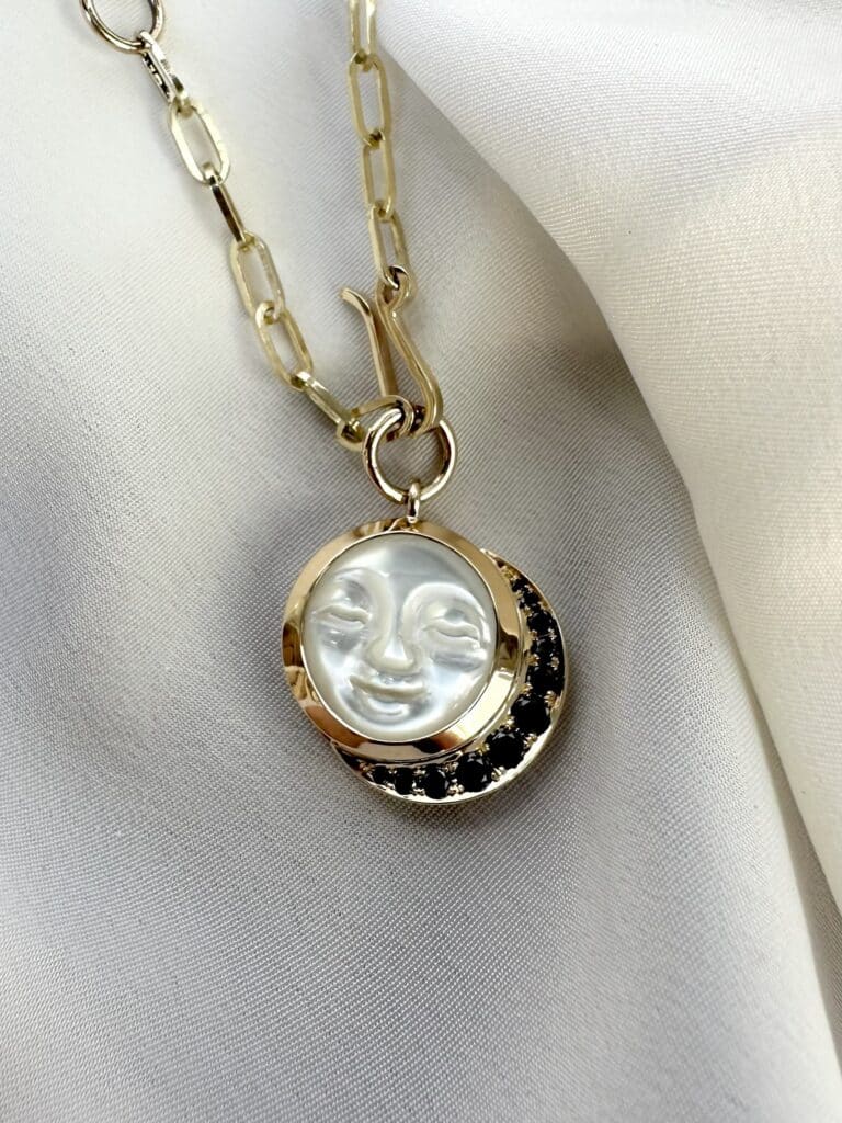 ‘Eclipse’ pendant. Carved mother of pearl, crescent moon halo of black diamonds, 9ct yellow gold
